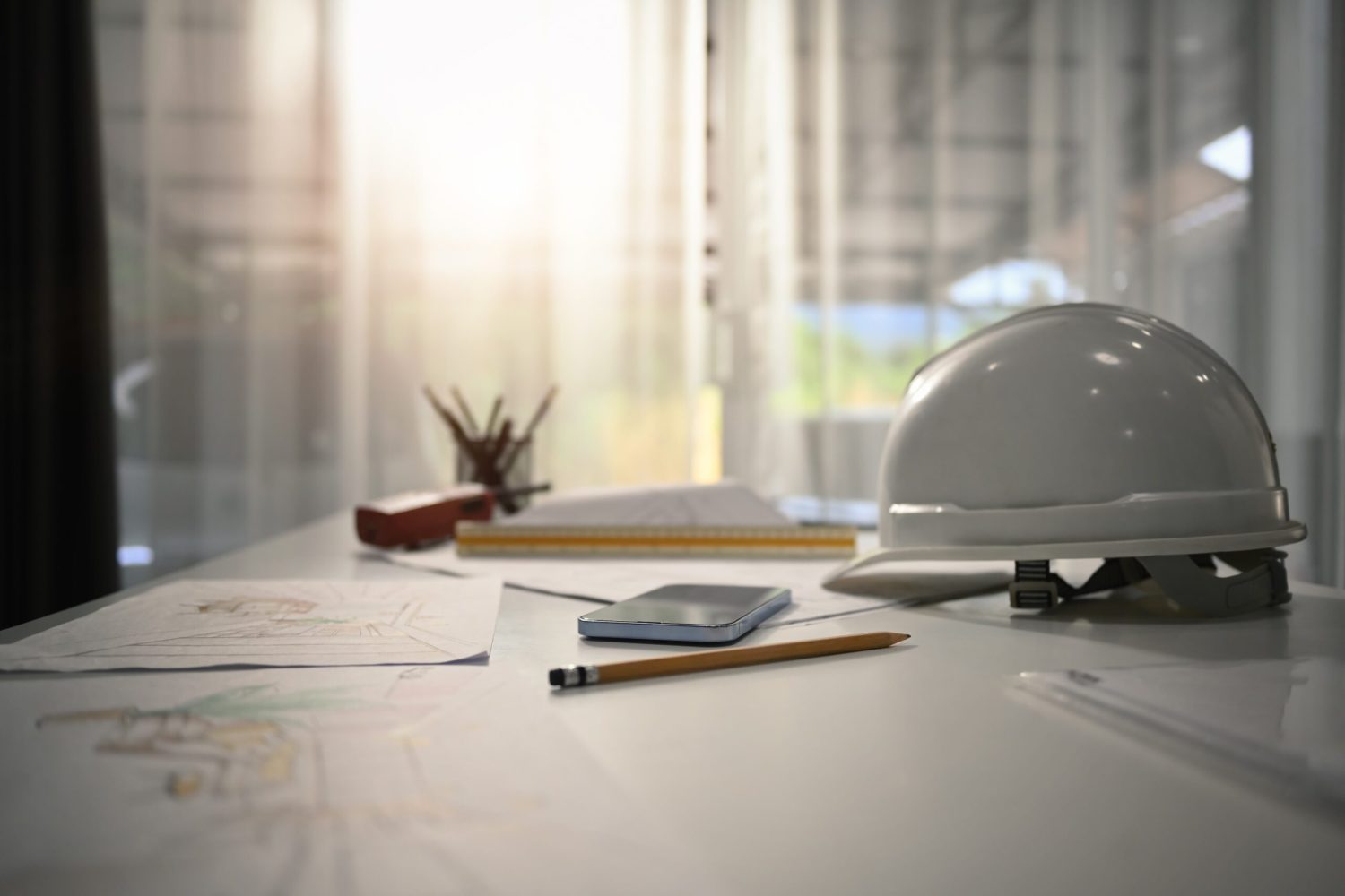 Safety helmets, blueprints and smartphone on the engineering desks. Engineering tools, workspace concept.
